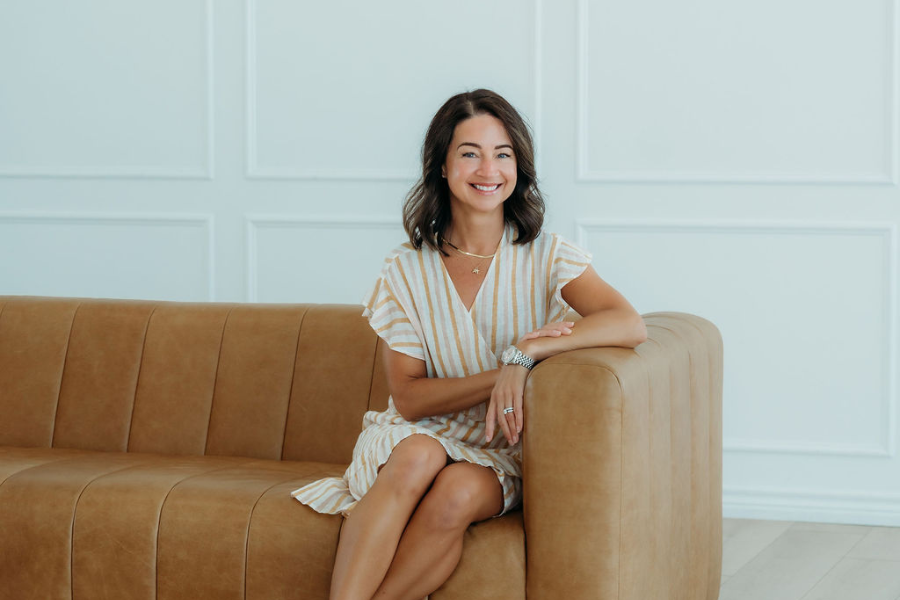 Sarah Phillipe seated on a tan couch in a bright, softly lit room